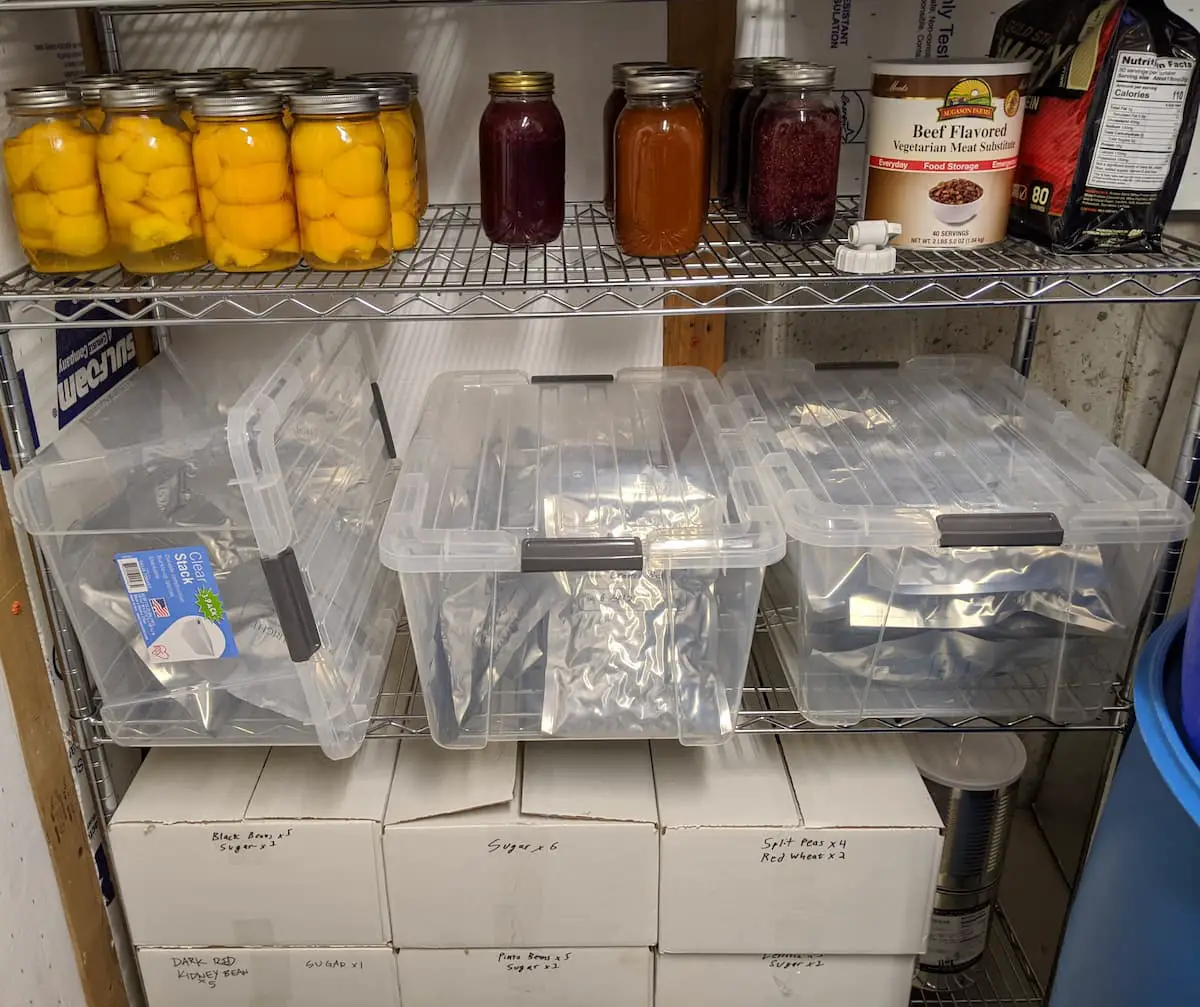 An image of jars of peaches, jams, and mylar bags inside a transparent box container found in a food storage area.