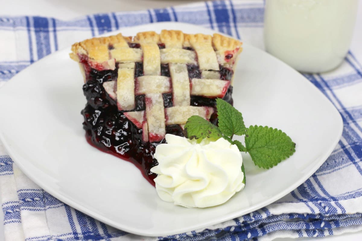 Homestead Blackberry Pie Recipe 6 image of a slice of blackberry pie with whipped cream