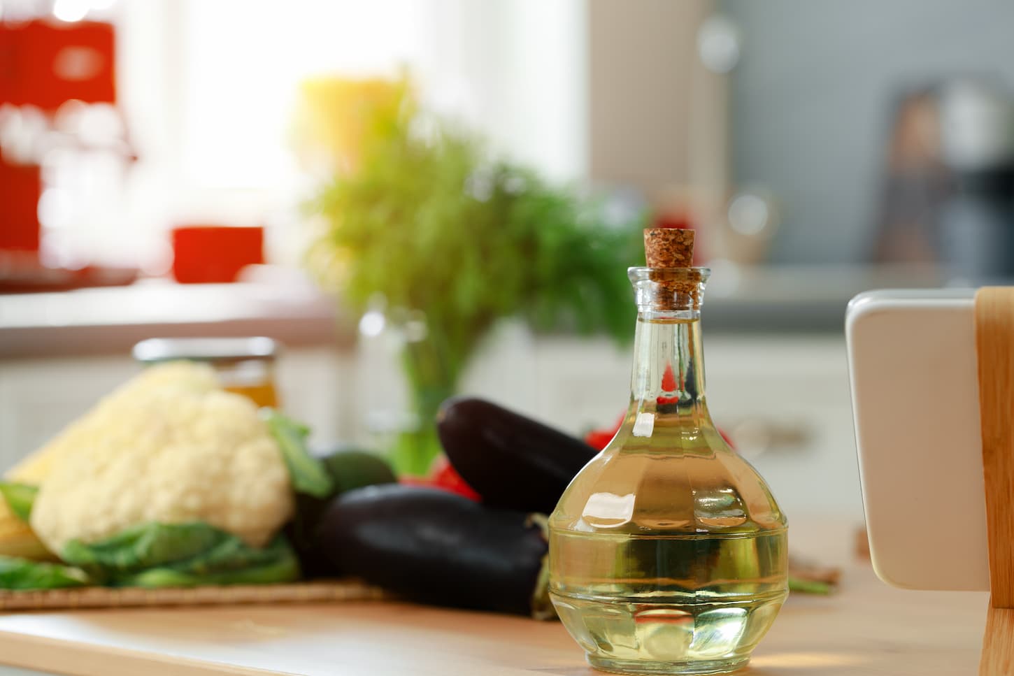 An image of glass bottle of oil on wooden kitchen counter.