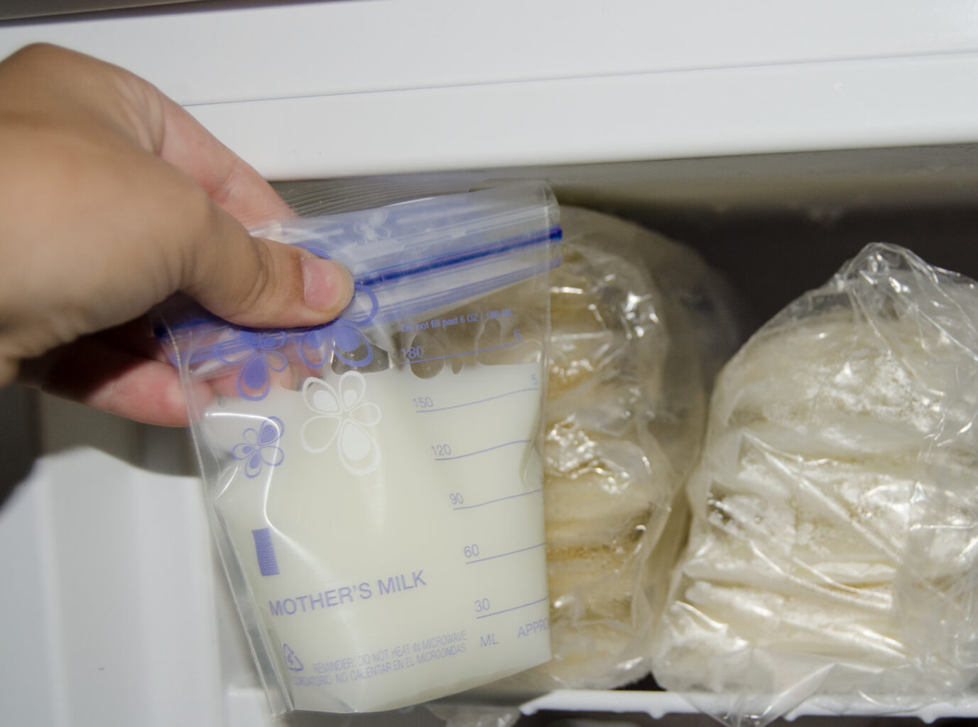 An image of mother putting expressed breast milk in the freezer for storage.