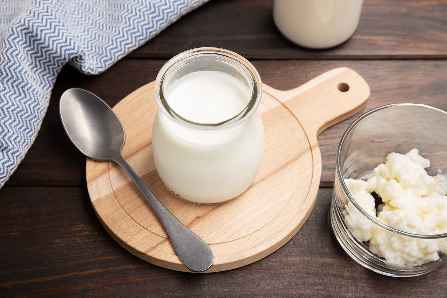 An image of healthy yogurt and kefir grains in glass on a wooden table.