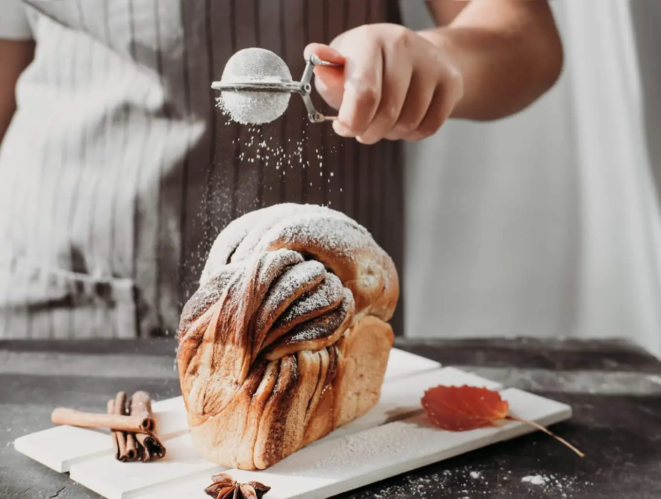An image of an artisan sourdough cinnamon swirl bread on a wooden rack.