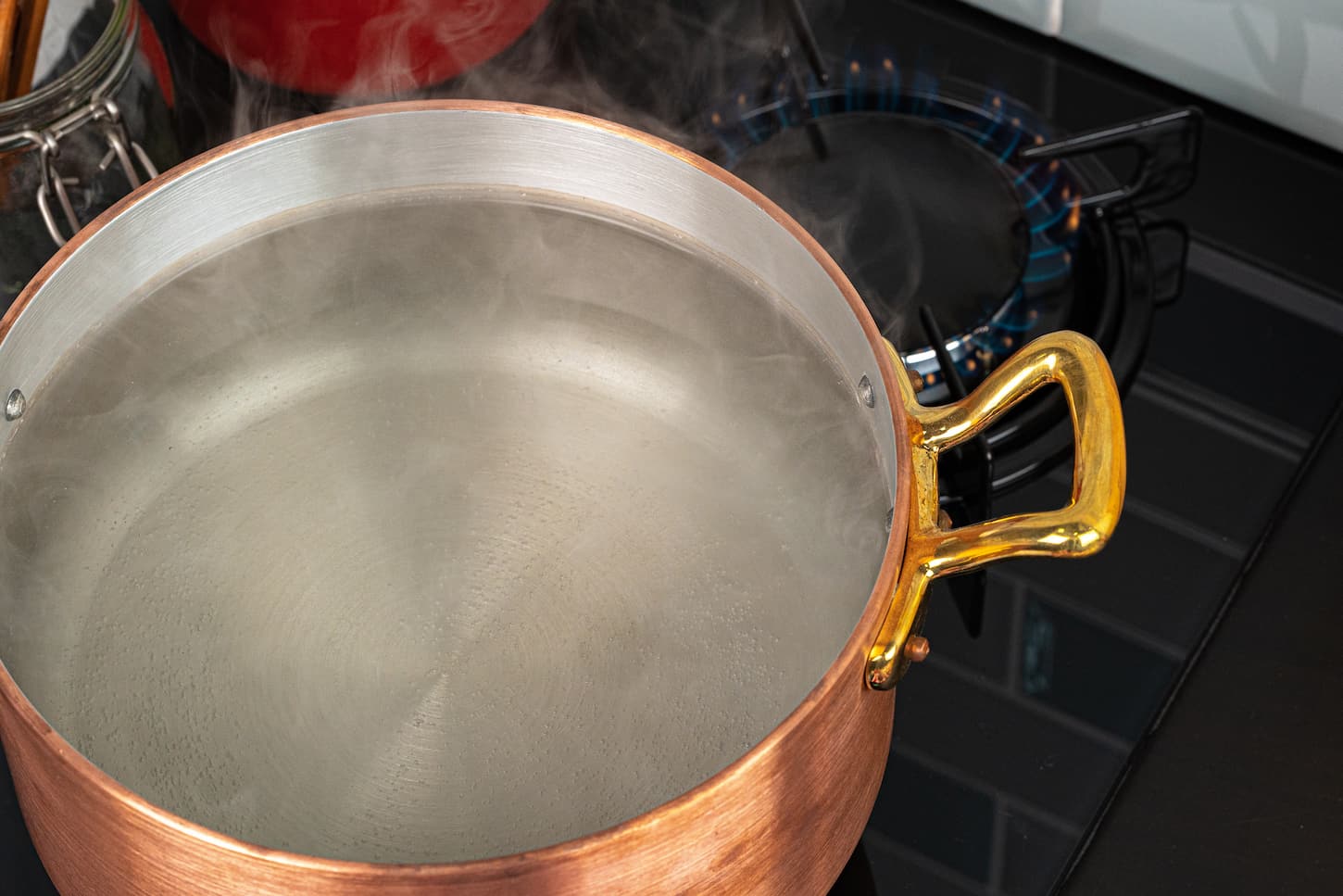 An image of a Copper pot with boiling water on a gas stove.