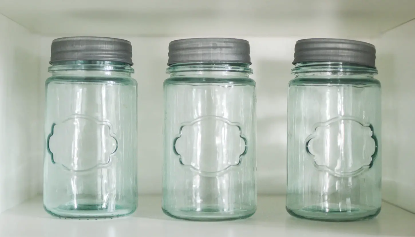 An image of three mason jars lined up inside a storage cabinet.