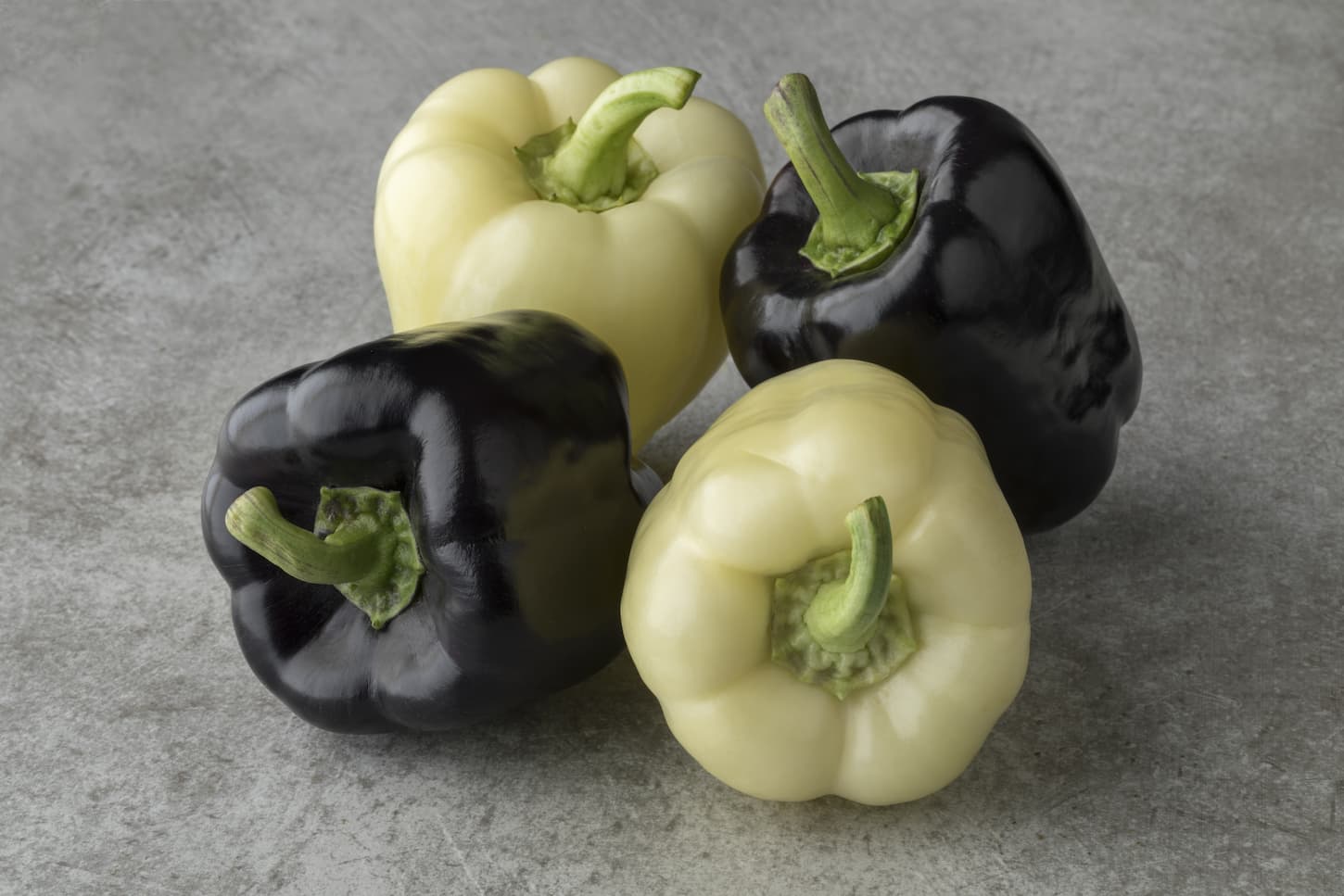 An image of purple and white bell peppers on a gray background.
