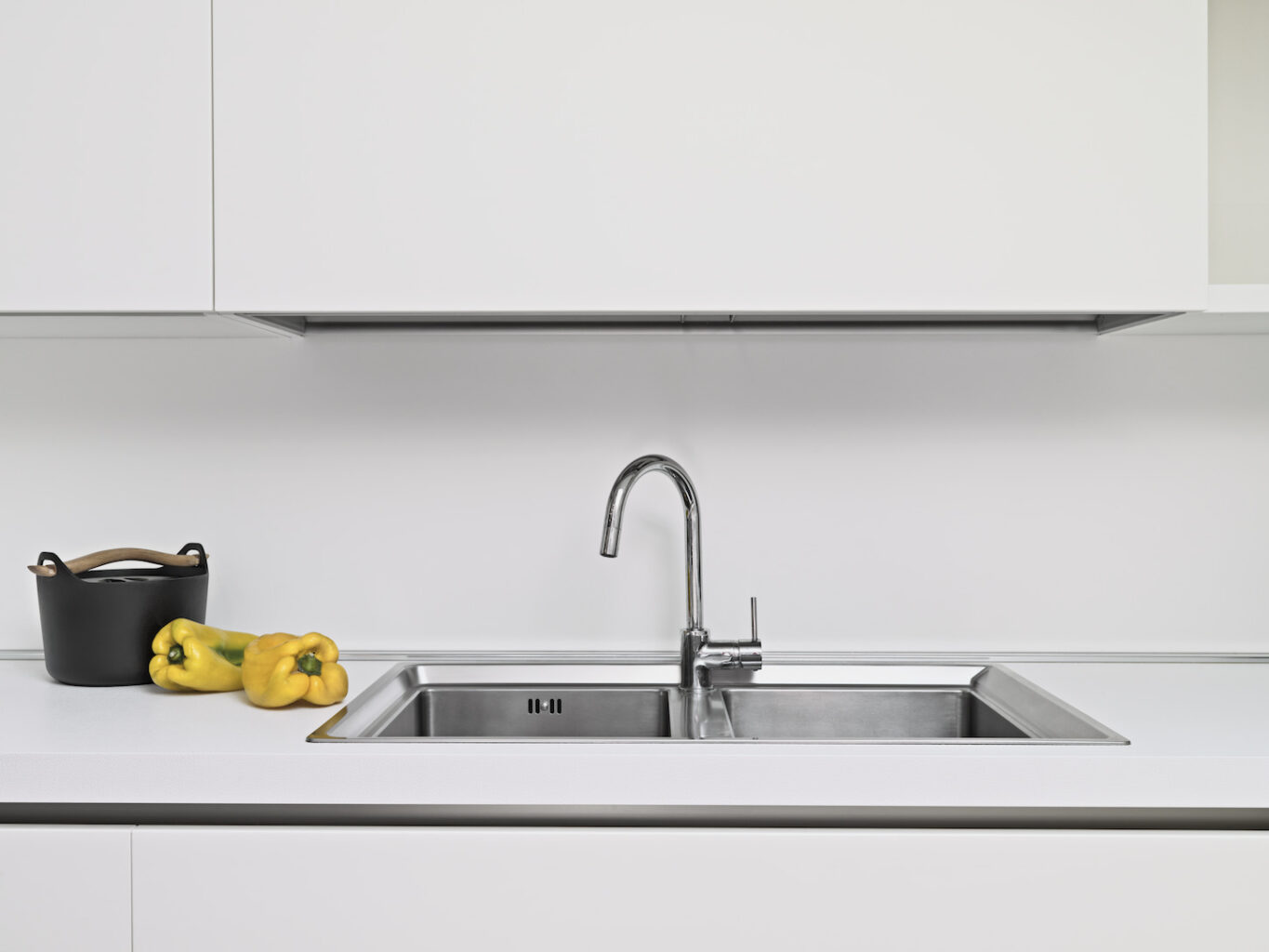 An image of a steel sink in a modern kitchen with objects near the sink.