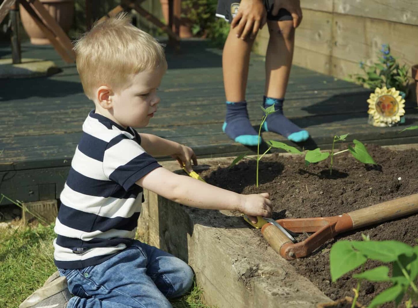 An image of two young boys planting runner beans in a raised bed made in stone.