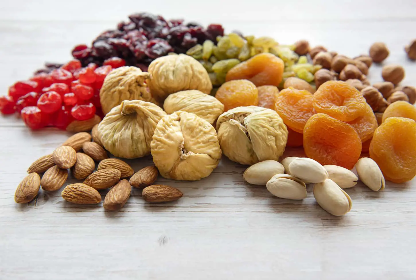 An image of Various dried fruits and nuts on a wooden background.