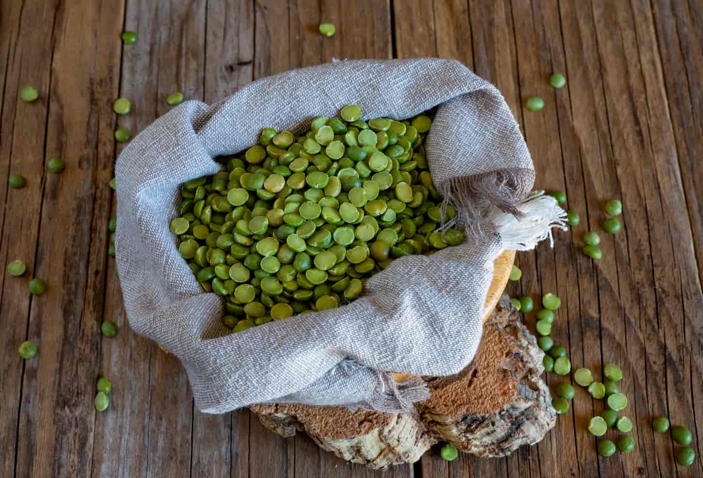 An image of a sack of split green peas on a wooden table.